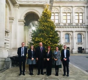 Guests stand in front of a Christmas tree outside government offices in London.
