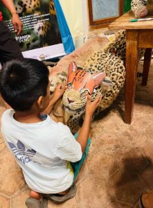 Child places a paper mask on a jaguar model toy