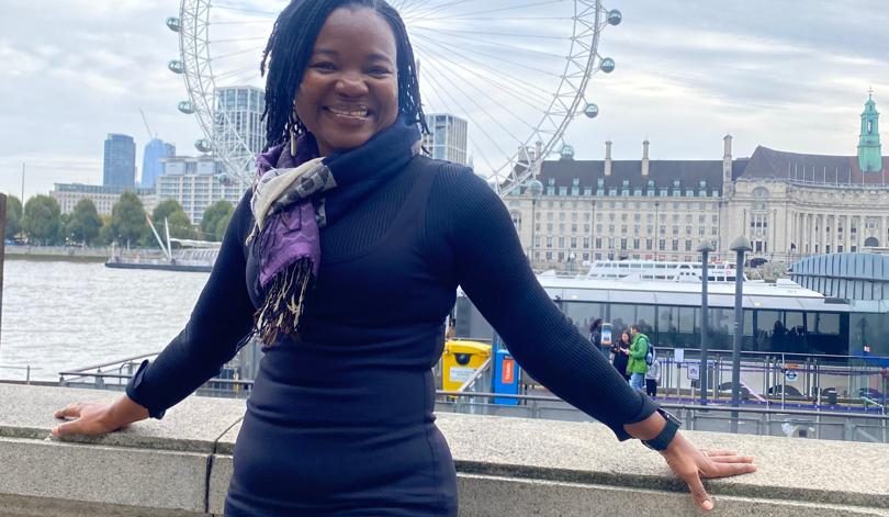 A woman smiling and leaning with the London eye behind her
