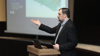 Alumnus presenting at lecturn.