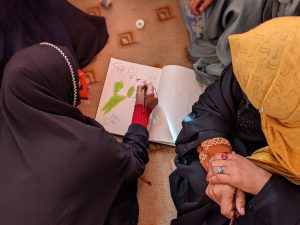 A woman draws a picture while another watches.