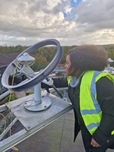 Margaret adjusts to a piece of technology while wearing a high visibility vest.