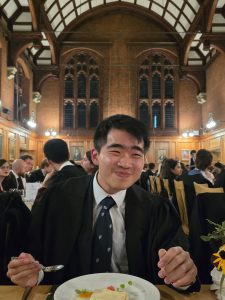 Aaron sits in a grand Cambridge dining room to eat a meal.